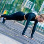 A sports girl performs a plank exercise to strengthen all muscle groups of the body