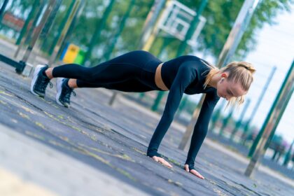 A sports girl performs a plank exercise to strengthen all muscle groups of the body
