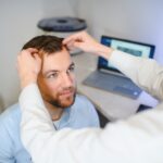 A trichologist examines the hair of a man who begins alopecia.