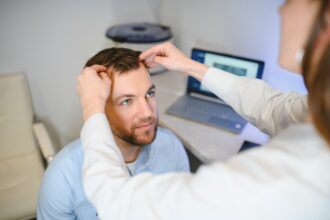 A trichologist examines the hair of a man who begins alopecia.