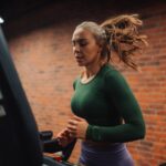 Determined sportswoman running on treadmill in modern gym