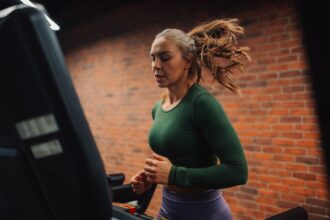 Determined sportswoman running on treadmill in modern gym