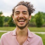 Joyful Young Man with Curly Hair Laughing in Park