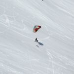 Person snowkiting down a snowy slope.