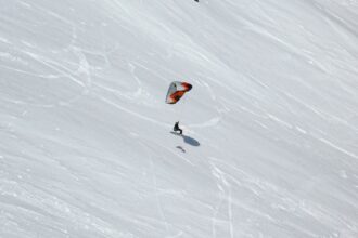 Person snowkiting down a snowy slope.
