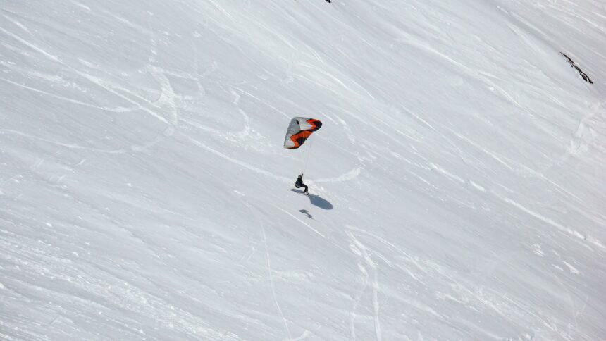 Person snowkiting down a snowy slope.