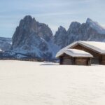 Snow covered landscape with some cabins and the mountains in the background