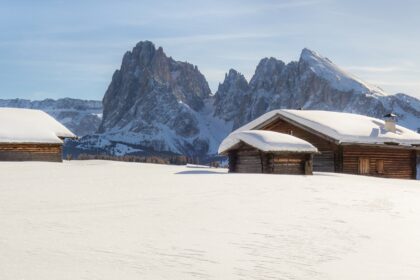 Snow covered landscape with some cabins and the mountains in the background