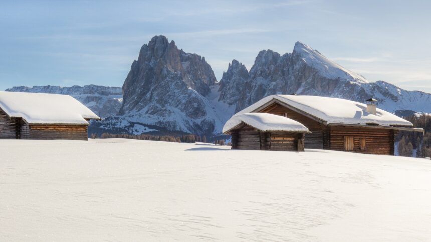 Snow covered landscape with some cabins and the mountains in the background