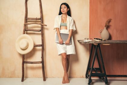 Successful asian businesswoman holding laptop, standing in home office in boho minimalistic style